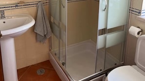 Ein Badezimmer mit Duschkabine, Waschbecken und Toilette.