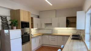 Eine moderne Küche mit weißen Schränken, einer Holzarbeitsplatte und einem eingebauten Backofen.