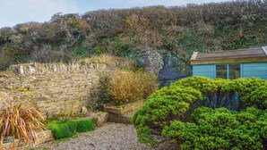 A stone wall, gravel path, and a small wooden structure with a blue roof. - 2 bedroom accommodation in Mawgan Porth (Mawgan Porth)