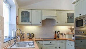 A kitchen with white cabinets, a stainless steel sink, and a built-in oven. - 2 bedroom accommodation in Mawgan Porth (Mawgan Porth)