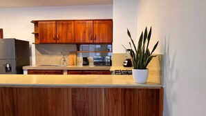 Een moderne keuken met houten kastjes, een roestvrijstalen koelkast, een koffiezetapparaat en een potplant.