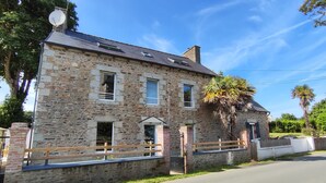 A stone building with a wooden fence, a gated entrance, and a clear sky. - TatîeMamîe, gîte Tata Jacqueline : grand gîte rénové proche mer, Bretagne (Plouha)