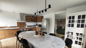 A modern kitchen with a marble island, black chairs, and a dining area. - TatîeMamîe, gîte Tata Jacqueline : grand gîte rénové proche mer, Bretagne (Plouha)