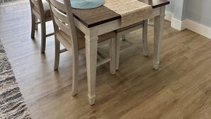 Un comedor con una mesa dispuesta para cuatro personas, rodeada de sillas de madera.