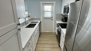 Una cocina moderna con armarios blancos, electrodomésticos de acero inoxidable y piso de madera.