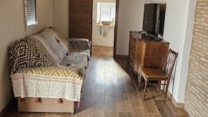 A room with a sofa set, a wooden cabinet, and a television.
