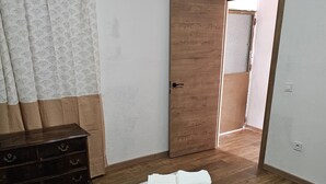 A bedroom with a bed, a wooden dresser, and a door leading to another room.
