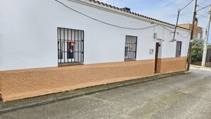 A building with a white facade and a brown base, featuring barred windows and a door.