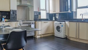 Une cuisine moderne avec un coin repas, comprenant une cuisinière, un four, un lave-linge et une table à manger avec des chaises.