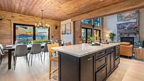 Una cucina moderna con una grande isola, soffitto in legno e camino in pietra.
