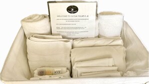 Un panier d’accueil en osier contenant une carte de bienvenue, des serviettes et des articles de toilette.