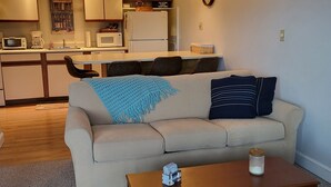 Un salon avec un canapé, une table basse et une cuisine en arrière-plan.
