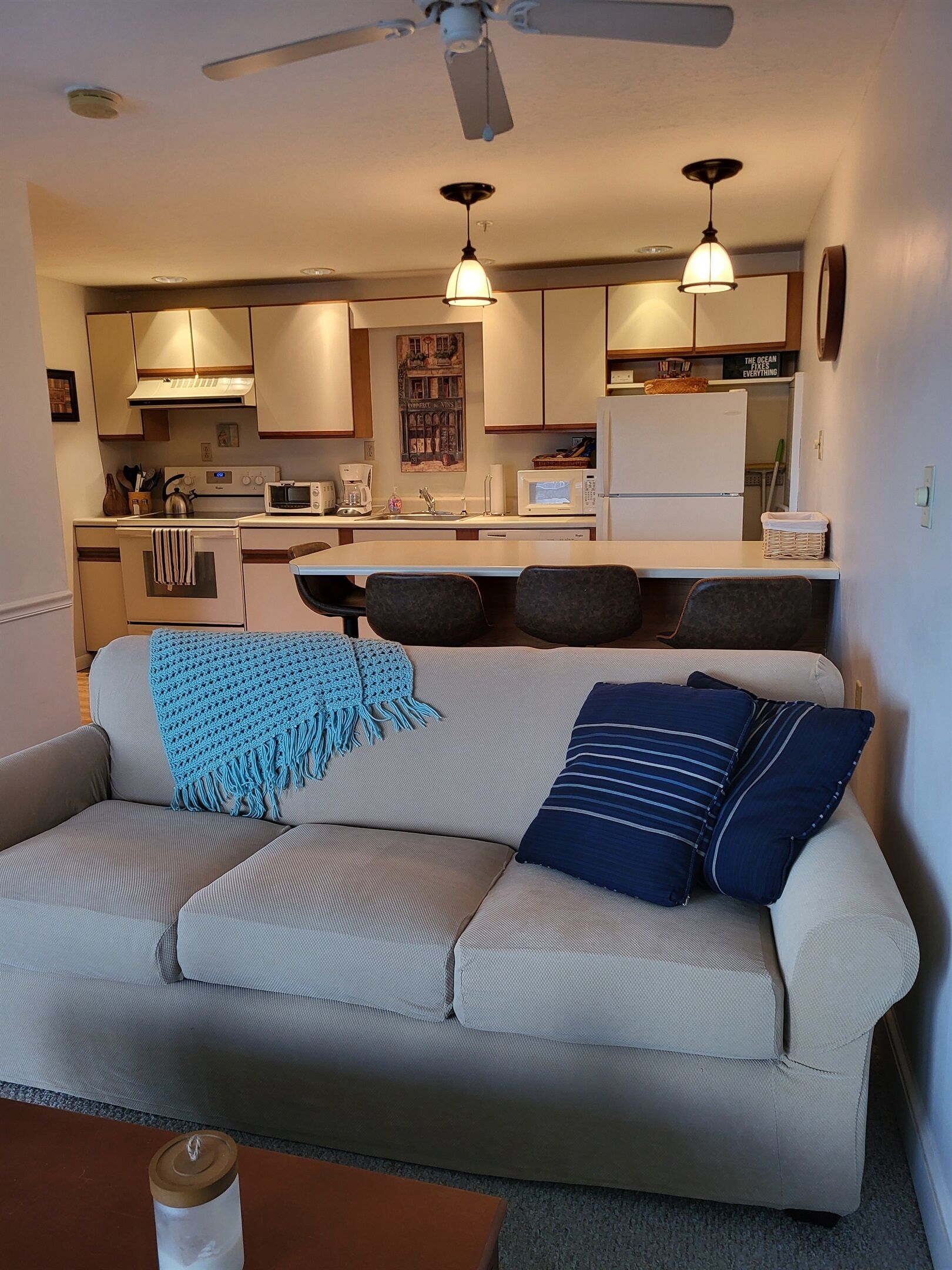 A living room with a sofa, a coffee table, and a kitchen in the background.