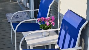 A white outdoor seating area with blue chairs and a table. - Located just steps from Wells Beach, Eastwinds 123 is perfect for your getaway. (Wells)