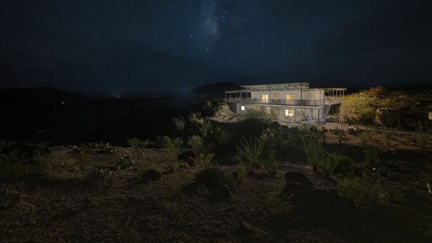 A remote, two-story building with a balcony, surrounded by sparse vegetation and under a starry night sky. - Willow Mtn. Ridge: Luxury & seclusion 10mi to BBNP (Terlingua)