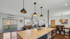 A modern kitchen with a wooden island, pendant lights, and a view to the outside. - Willow Mtn. Ridge: Luxury & seclusion 10mi to BBNP (Terlingua)
