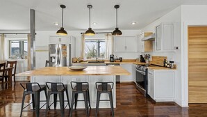 A modern kitchen with a central island, bar stools, pendant lighting, and a view of the outdoors. - Willow Mtn. Ridge: Luxury & seclusion 10mi to BBNP (Terlingua)
