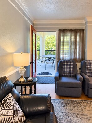 A living room with a sofa, two armchairs, a table with a lamp, and a view of an outdoor patio with a table and chairs. - Spacious 3BD, 3BA Condo with En Suite Bathrooms, 10 min Walk to Anakeesta (Gatlinburg)