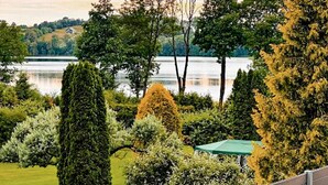 A landscaped garden with various trees and a bench, overlooking a body of water. - Pet friendly home in Zawory with sauna (Zawory)