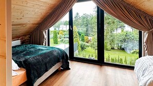A bedroom with a large window, a bed, and a view of a garden. - Pet friendly home in Zawory with sauna (Zawory)