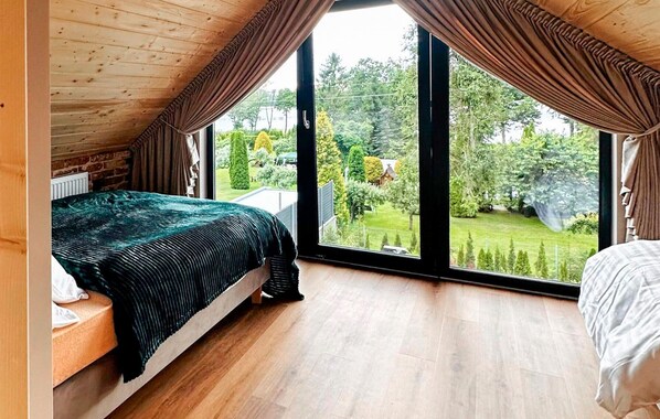 A bedroom with a large window, a bed, and a view of a garden.