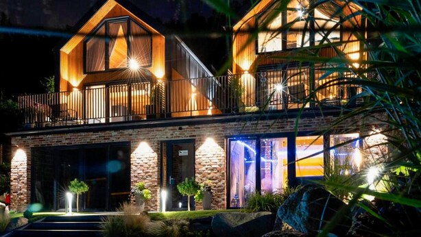 A two-story house with a stone facade, a balcony on the upper floor, and a well-lit entrance. - Pet friendly home in Zawory with sauna (Zawory)