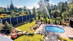 A backyard with a swimming pool, a grassy lawn, and a variety of plants and trees. - Pet friendly home in Zawory with sauna (Zawory)