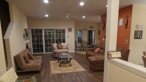 A spacious living room with a large window, a fireplace, and a dining area.