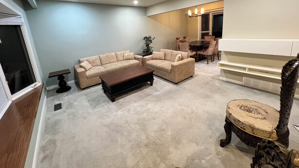A living room with two sofas, a coffee table, and a dining area with a table and chairs.