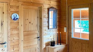 A wooden cabin interior with a door, a window, and a small table with a candle.