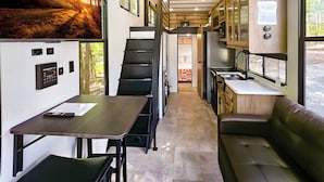 Een compact camperinterieur met een kitchenette, een eethoek en een zithoek.