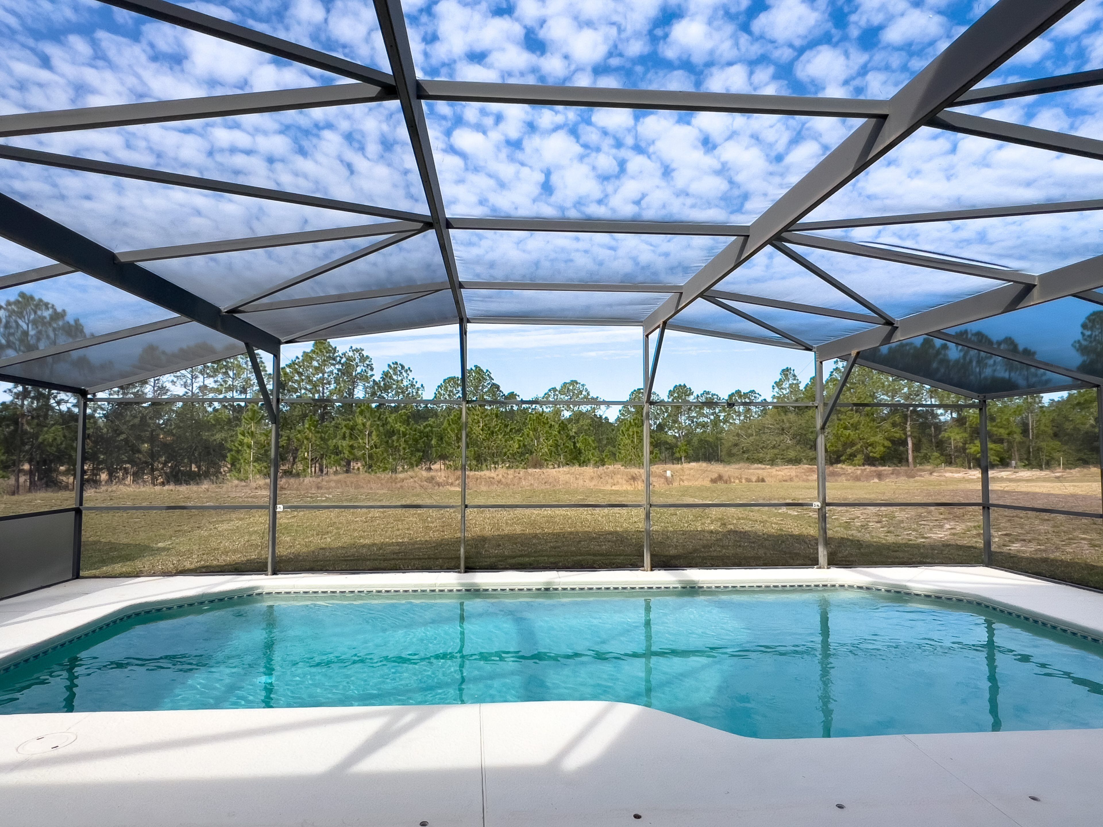 Piscina techada con vistas a árboles y un cielo despejado.