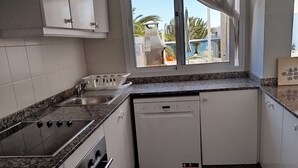 A modern kitchen with white cabinets, a granite countertop, a built-in oven, and a dishwasher. - Dream getaway! seaview shell (Playa Honda , lanzarote)