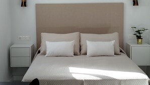 A modern bedroom with a large bed, two bedside tables, a nightstand, and a potted plant. - Dream getaway! seaview shell (Playa Honda , lanzarote)