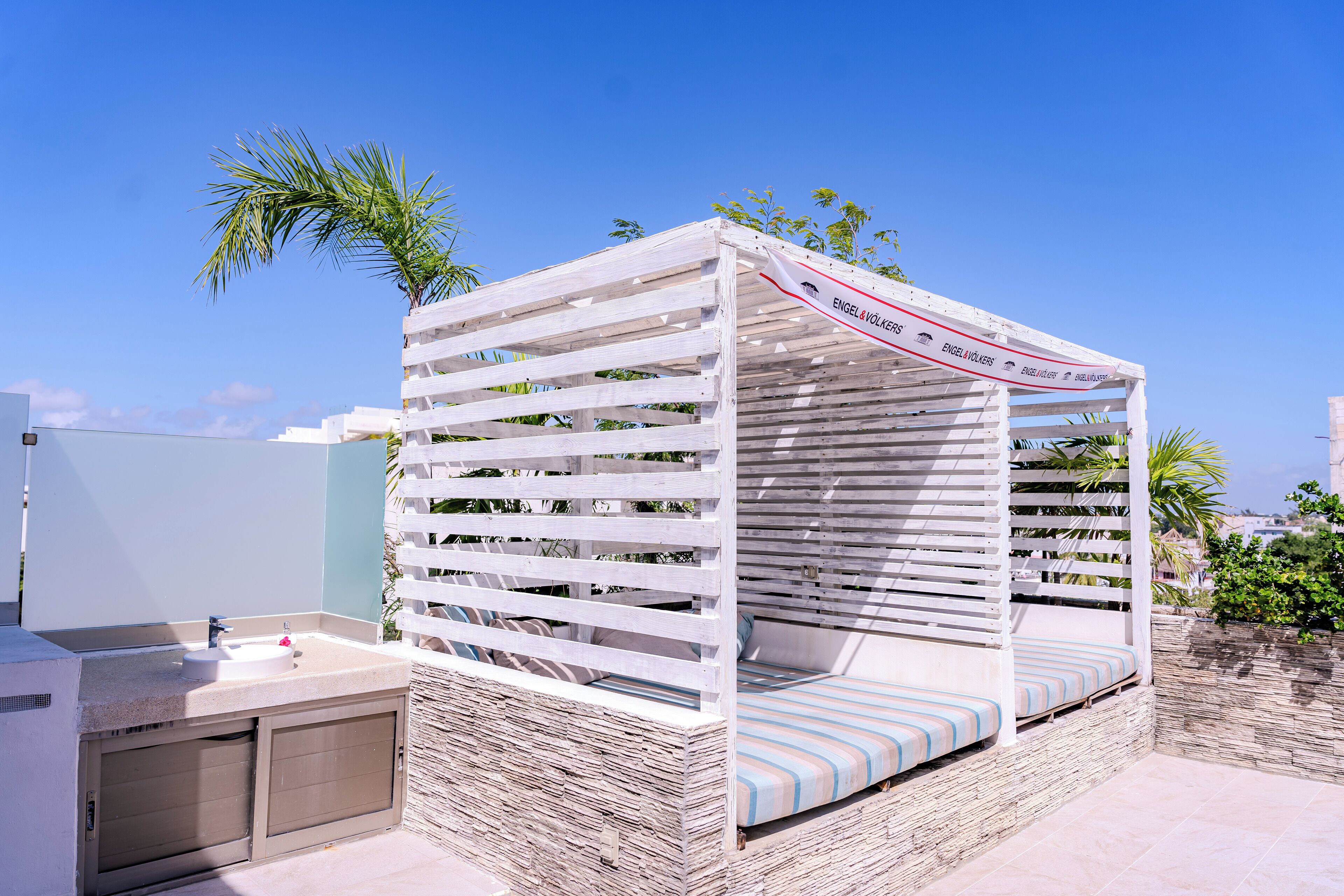 A small, enclosed outdoor seating area with a bench and a sink.