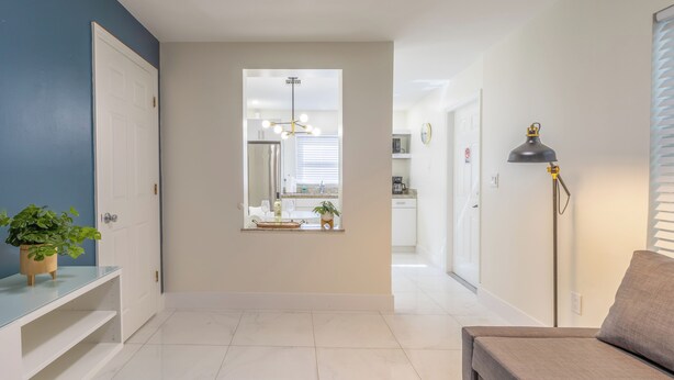 A hallway with a white door, a potted plant, a bench, and a floor lamp. - 4 Guest, 5 minutes from all the attractions in Miami,Airport, Downtown, Wynwood (Miami)
