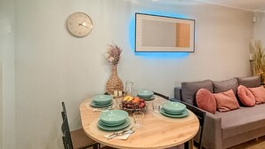 A dining area with a round wooden table set for four, a clock on the wall, and a modern art piece above the table. - Pet friendly home in Ostroda with WiFi (Ostroda)