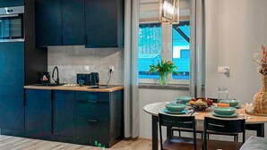A modern kitchen with dark cabinetry, a built-in oven, and a dining area with a table set for two. - Pet friendly home in Ostroda with WiFi (Ostroda)
