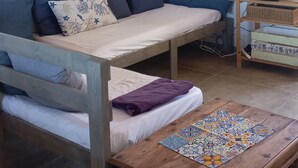 A cozy room with a bed, a sofa, a wooden table, and a TV stand.