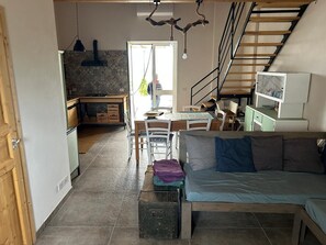 Un intérieur chaleureux avec un lit, un coin repas et un escalier.