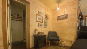 Ein gemütliches Zimmer mit Holzwänden, Kamin, Sessel und Teppich.