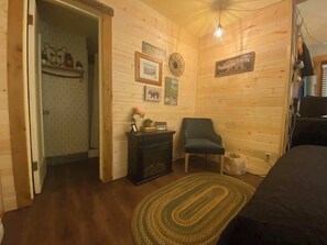 Una habitación acogedora con paredes de madera, chimenea, una silla y una alfombra.