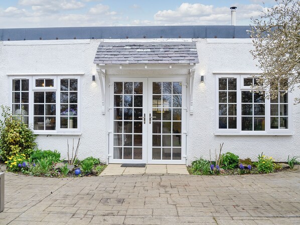 A white building with a tiled roof, a central door with glass panels, and multiple windows.