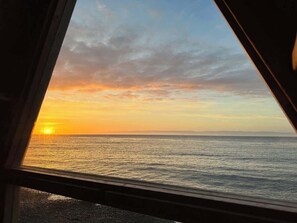 Vista al atardecer desde una ventana con vista al agua.