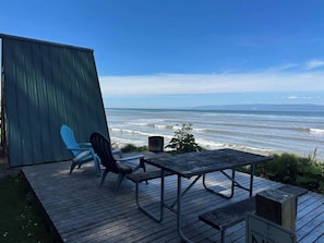 Une terrasse en bois avec une table et deux chaises, d’où l’on a une vue sur l’océan.