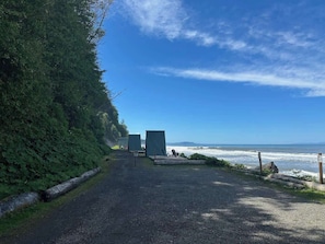 Un sendero de grava que conduce a construcciones frente al mar, con vista al océano.