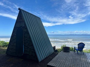 Eine Holzterrasse mit einer Metallkonstruktion und einem blauen Stuhl, der auf das Meer ausgerichtet ist.
