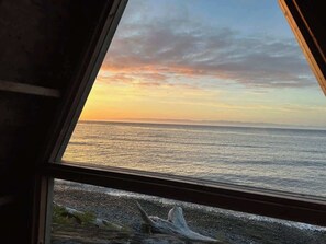 Blick auf das Meer durch ein Fenster mit Holzrahmen.