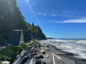 En strand med en liten byggnad, en stol och en trädstam.