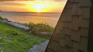 A sunset view from a wooden structure overlooking a body of water. - Whiskey Creek Beach Front A-Frame Site 11 (Port Angeles)